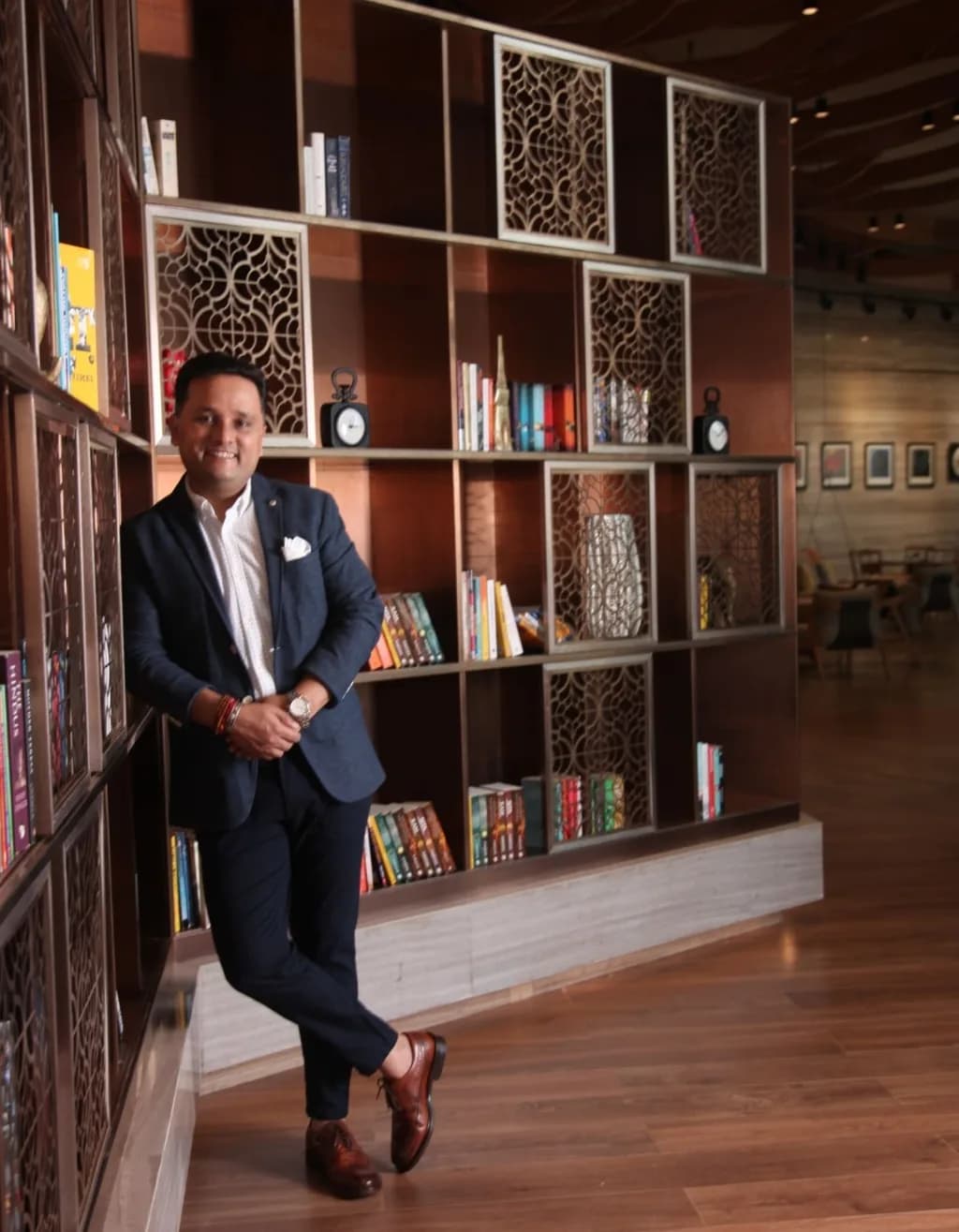 Amish Tripathi standing beside a bookshelf
