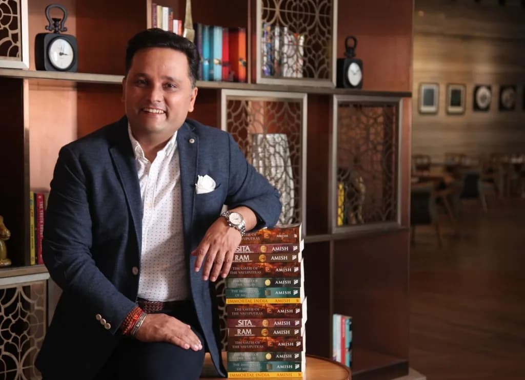 Amish Tripathi standing in front of a bookcase